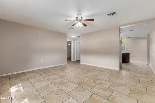 a view of an empty room and window and chandelier fan