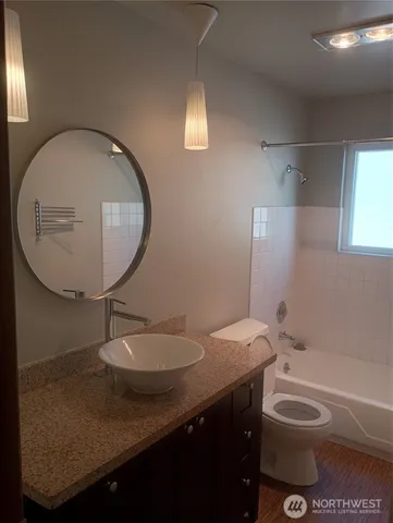 a bathroom with a granite countertop toilet sink and mirror
