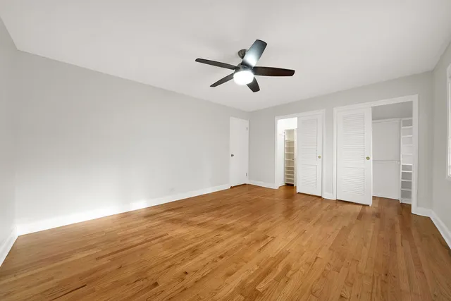 a view of empty room with wooden floor and ceiling fan