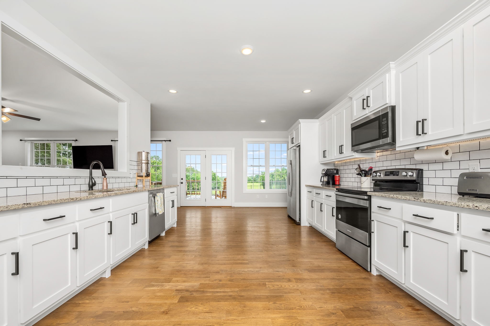 3880 Short Mountain Road Woodbury, TN 37190 - Photo 16 of 56 a large kitchen with stainless steel appliances kitchen island granite countertop a large stove top oven a sink dishwasher and white cabinets with wooden floor