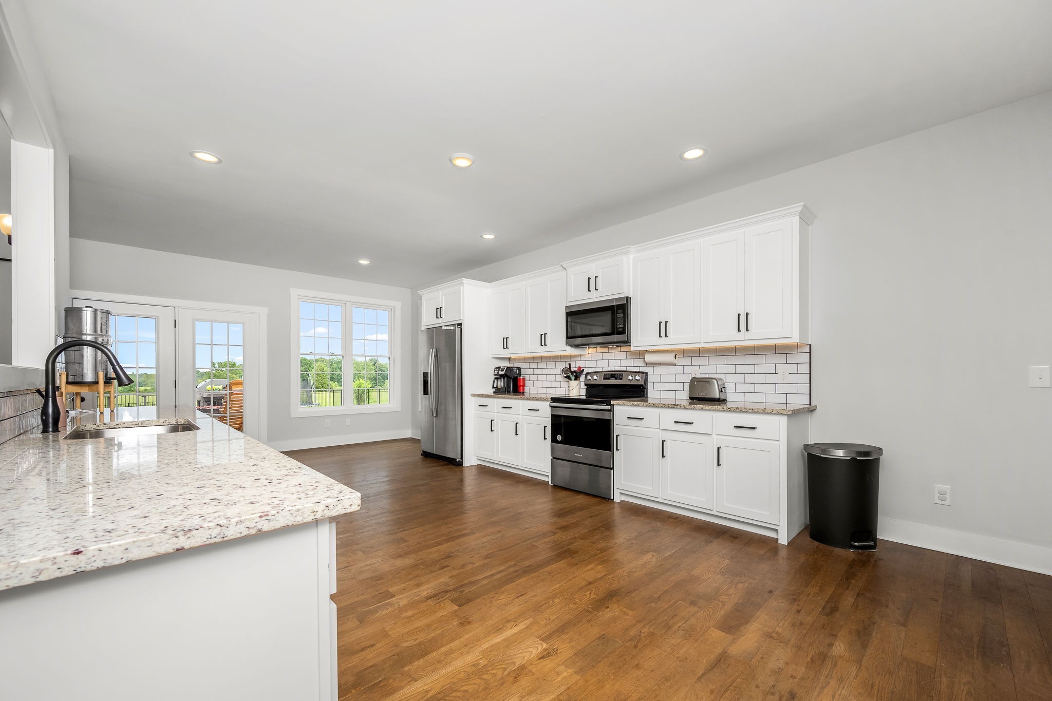 3880 Short Mountain Road Woodbury, TN 37190 - Photo 17 of 56 a kitchen with stainless steel appliances granite countertop a stove top oven a sink a refrigerator white cabinets and wooden floor