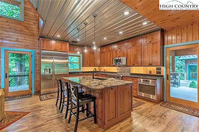 a kitchen with stainless steel appliances granite countertop table chairs sink and wooden floor