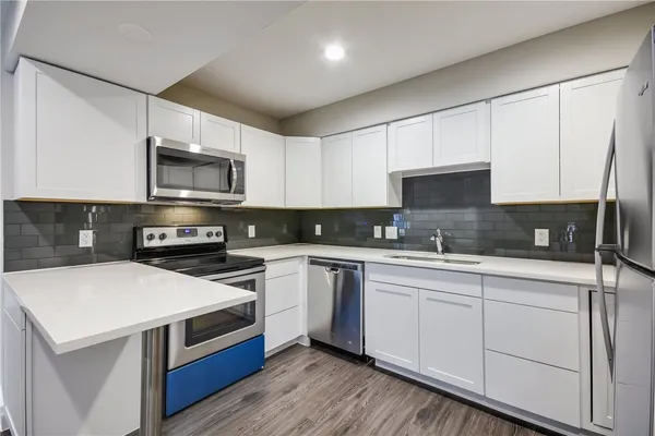 a kitchen with stainless steel appliances granite countertop a stove a sink a microwave and white cabinets