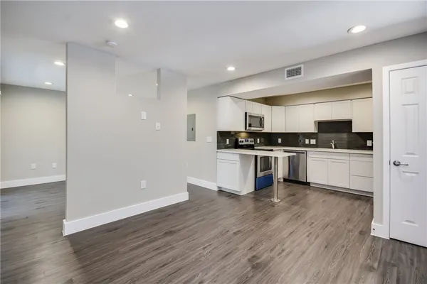 a kitchen with wooden floors and white cabinets
