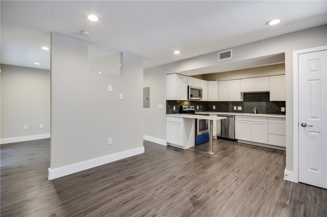 935 La Posada Drive, Unit 142 Austin, TX 78752 - Photo 4 of 28 a kitchen with wooden floors and white cabinets