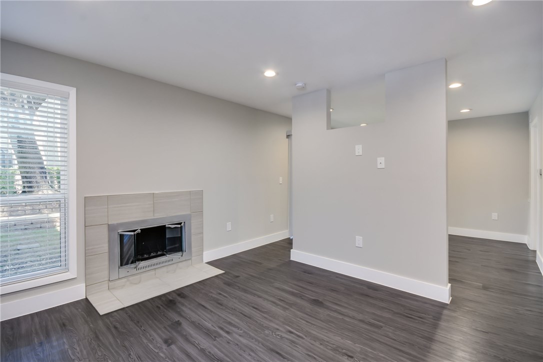 935 La Posada Drive, Unit 142 Austin, TX 78752 - Photo 8 of 28 an empty room with wooden floor and fireplace