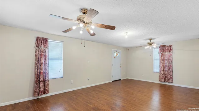 a view of a livingroom with a ceiling fan window and wooden floor