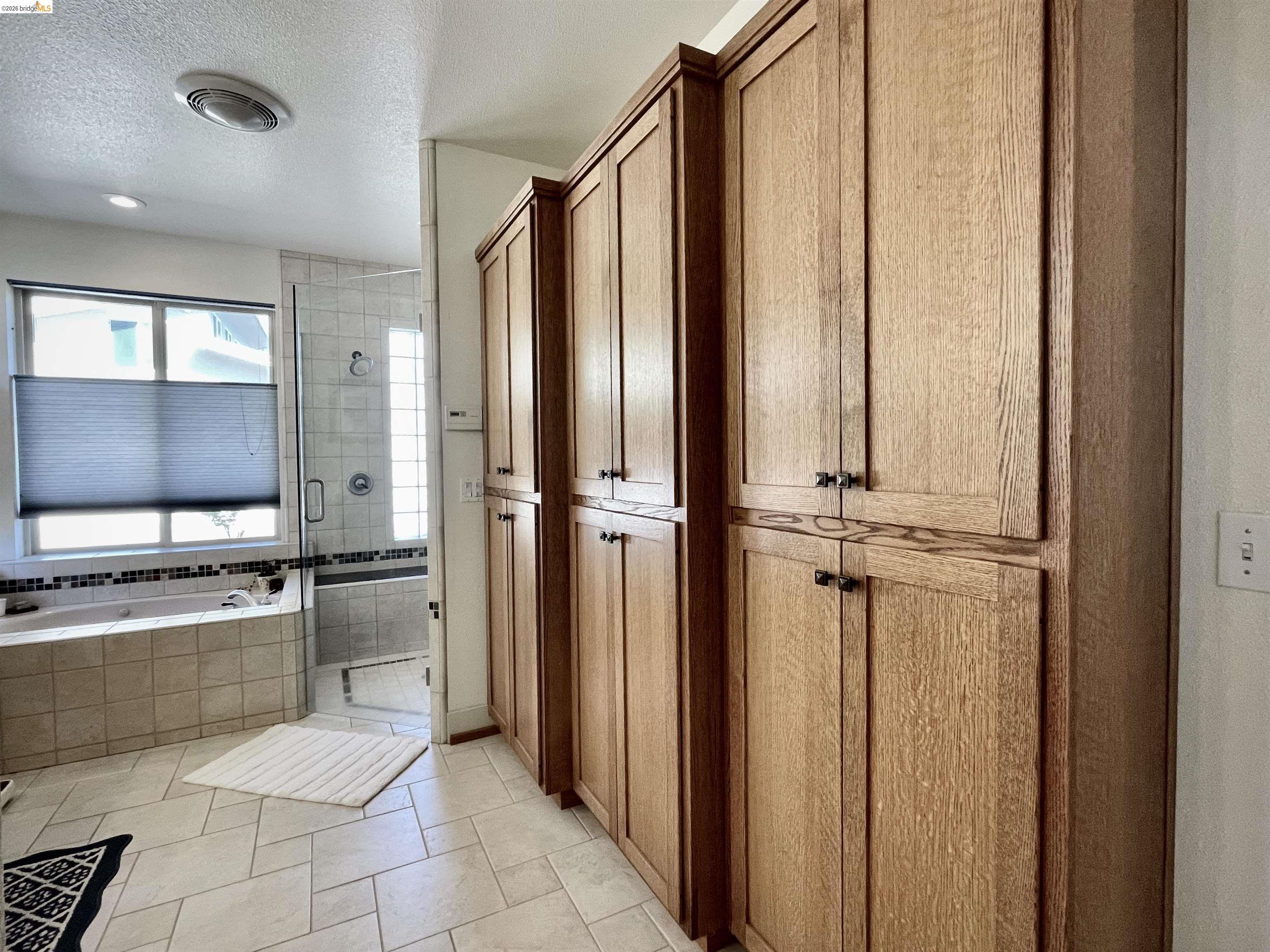 18288 Lambert Lake Road Sonora, CA 95370 - Photo 25 of 55 Bathroom featuring a textured ceiling, a stall shower, a bath, light tile patterned flooring, and a closet
