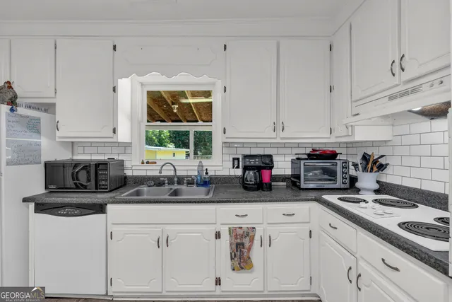 a kitchen with stainless steel appliances kitchen island granite countertop a table chairs sink and cabinets