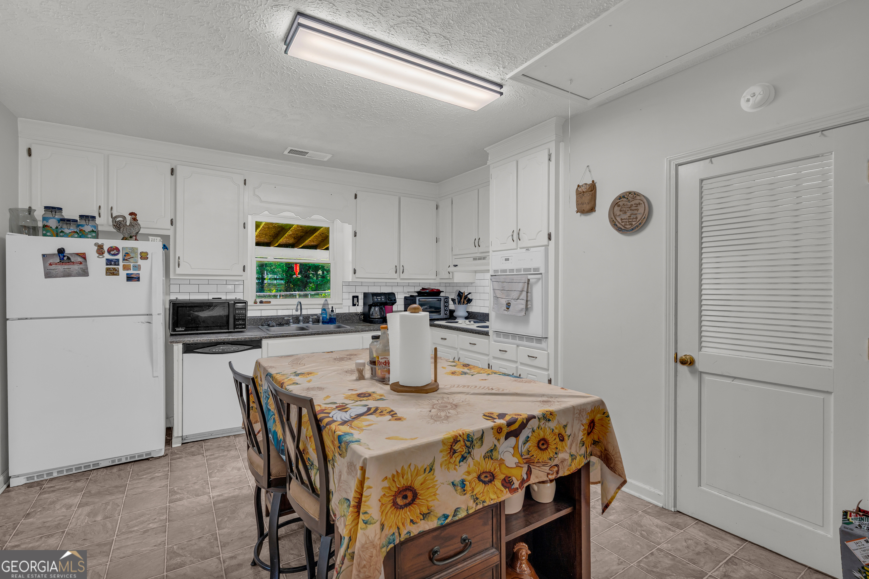 878 Jackson Street Locust Grove, GA 30248 - Photo 24 of 65 a kitchen with a table chairs refrigerator and microwave