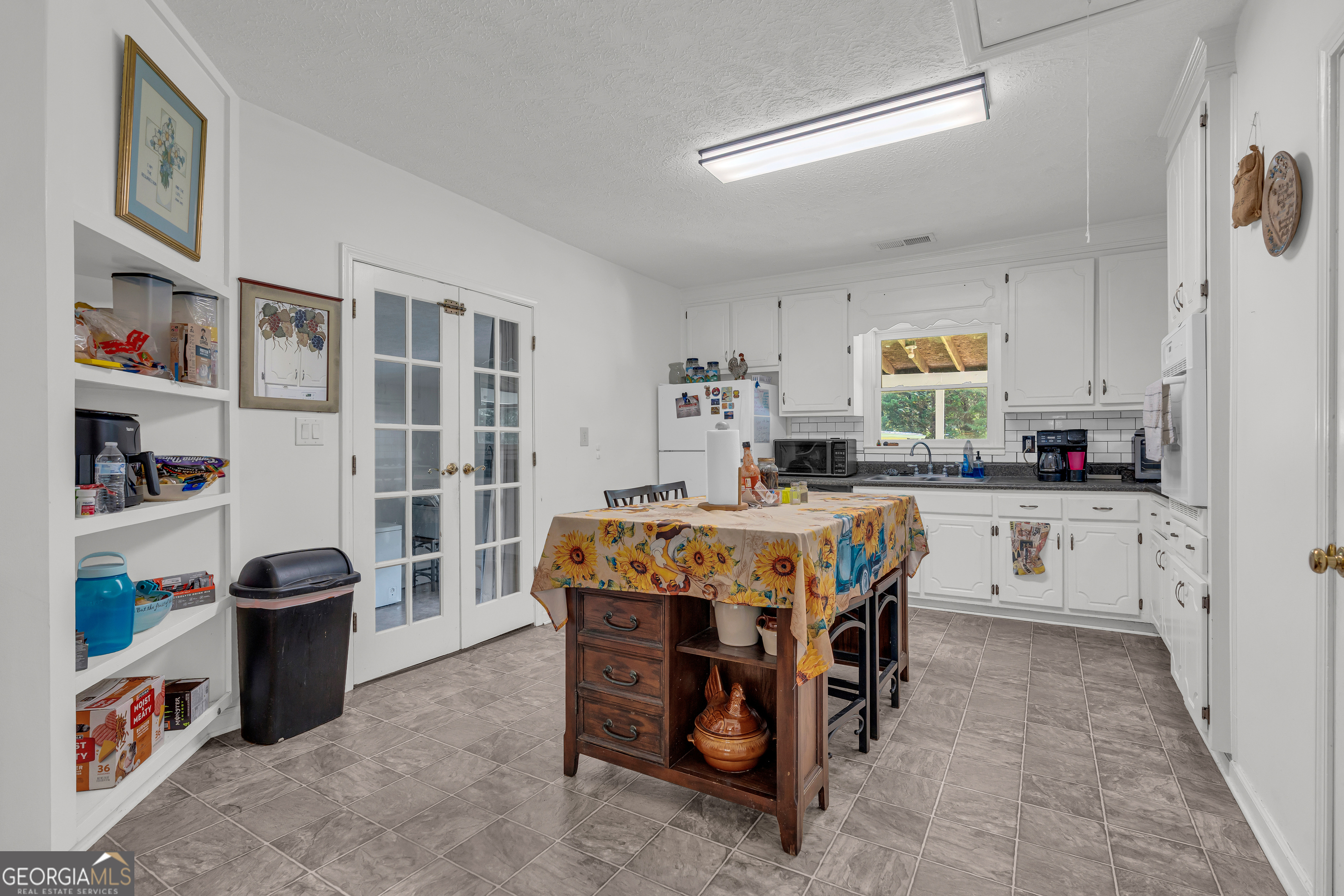 878 Jackson Street Locust Grove, GA 30248 - Photo 25 of 65 a kitchen with stainless steel appliances kitchen island granite countertop a table chairs sink and cabinets