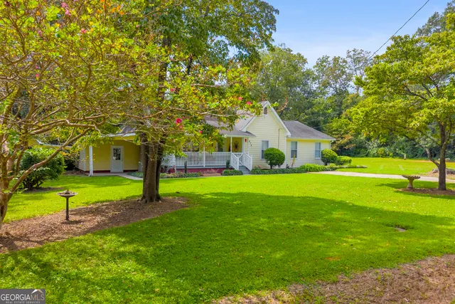 a front view of a house with garden and trees