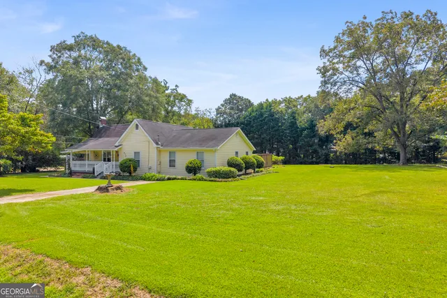 a front view of house with yard and trees in the background