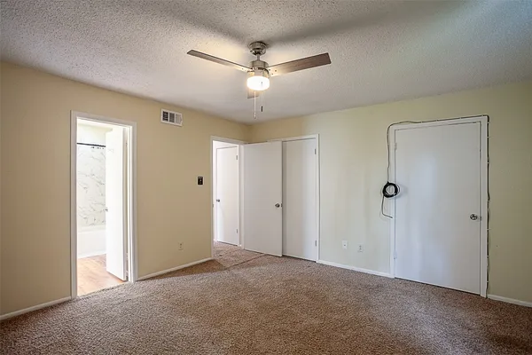 an empty room with closet and a ceiling fan
