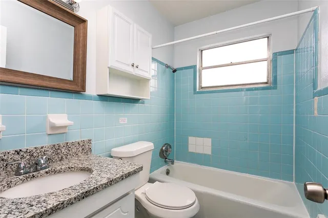 a bathroom with a granite countertop toilet sink and mirror