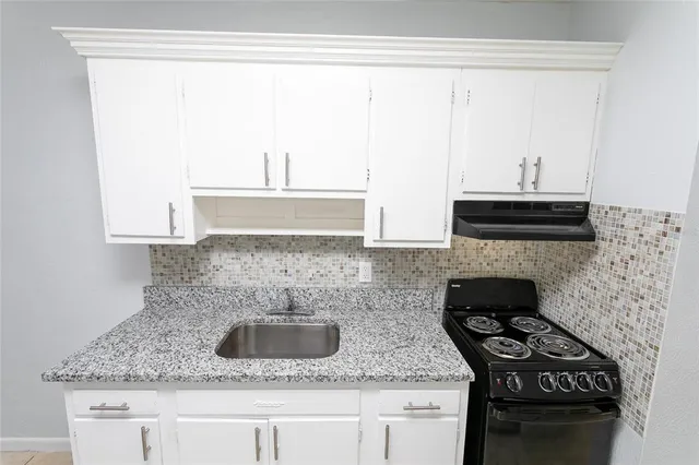 a kitchen with granite countertop a sink a stove and a microwave