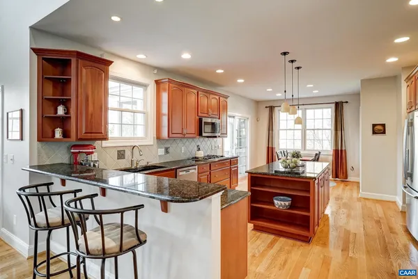 a kitchen with stainless steel appliances granite countertop a sink a stove and a wooden cabinets