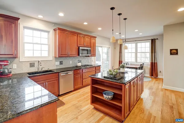 a kitchen with stainless steel appliances granite countertop a stove a sink dishwasher and cabinets with wooden floor