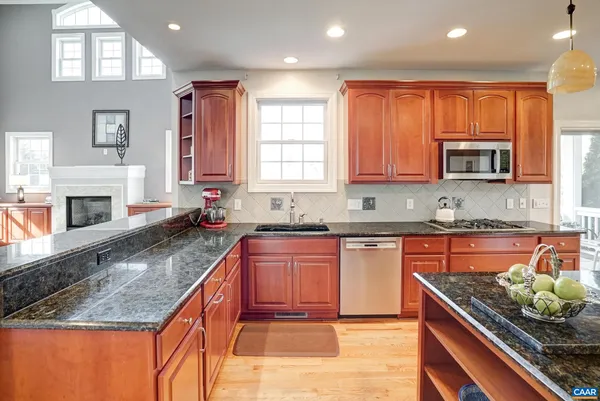 a kitchen with stainless steel appliances granite countertop a stove a refrigerator a kitchen island a table and chairs