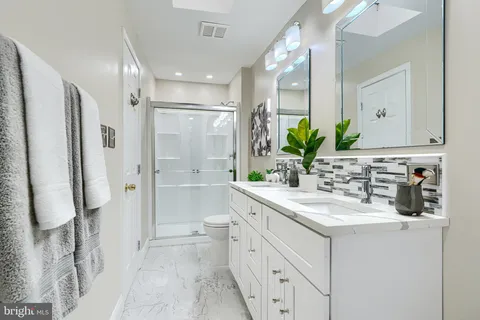 a bathroom with a double vanity sink mirror and shower