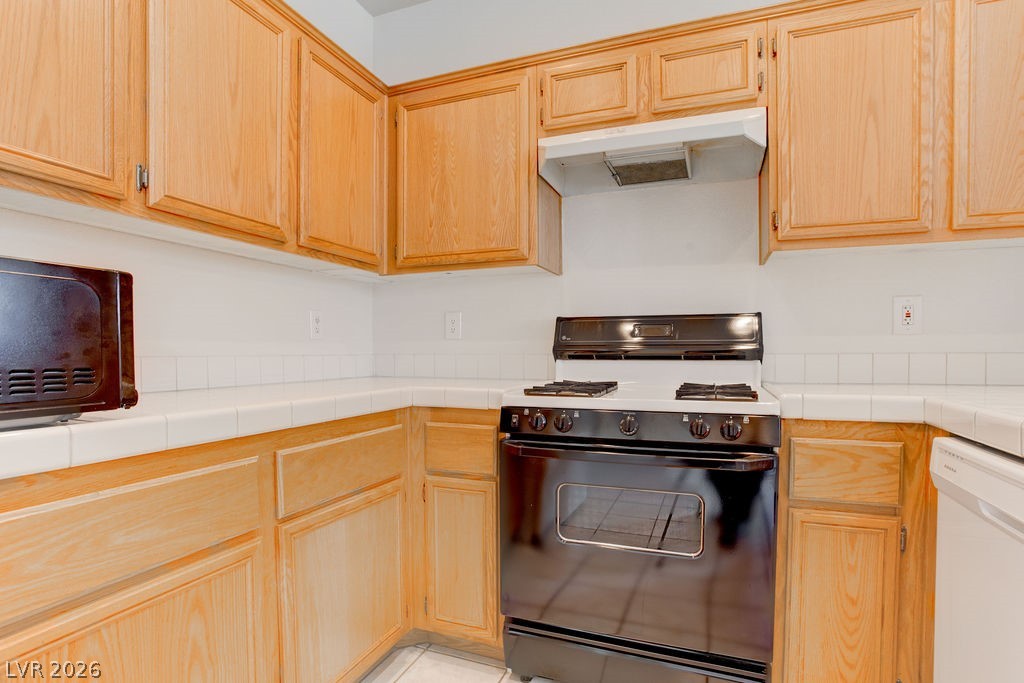 2201 Ramsgate Drive, Unit 326 Henderson, NV 89074 - Photo 25 of 44 Kitchen featuring tile counters, black gas range oven, and light wood finish cabinets