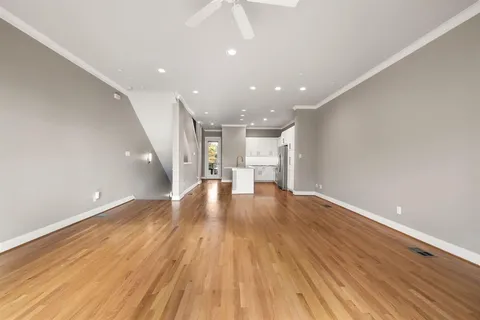 a kitchen with stainless steel appliances granite countertop a refrigerator a stove a sink and white cabinets with wooden floor