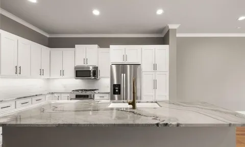 a large kitchen with stainless steel appliances granite countertop a stove a sink and a refrigerator