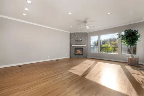 an empty room with wooden floor fireplace and windows