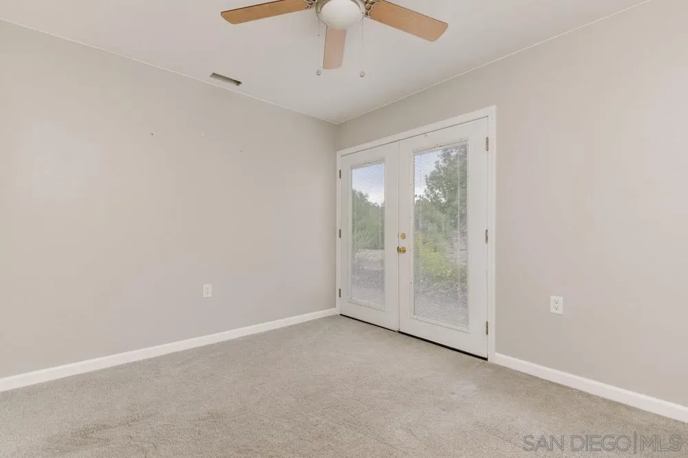 11949 Rocoso Road Lakeside, CA 92040 - Photo 11 of 27 an empty room with a chandelier fan and windows