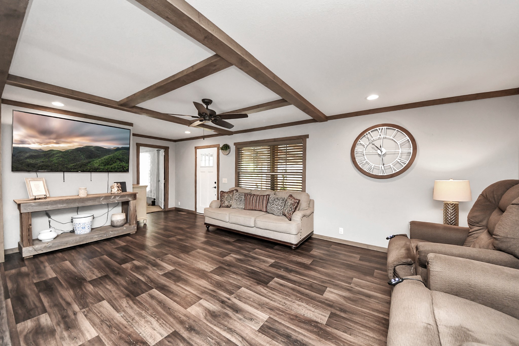 131 Kiowa Court Rosharon, TX 77583 - Photo 14 of 42 This living room features a modern rustic design with wood beam ceilings and dark vinyl floors. The space is well-lit with recessed lighting and a ceiling fan