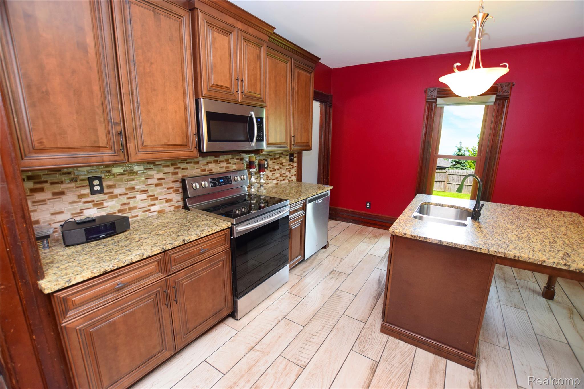 404 North Adelaide Street Fenton, MI 48430 - Photo 4 of 23 Kitchen featuring wood cabinetry, light-toned granite countertops, and a mosaic tile backsplash