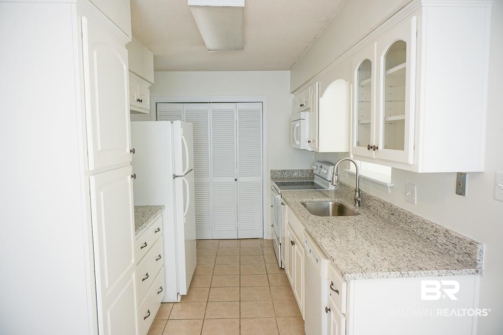 4377 Fathbrook Lane Mobile, AL 36693 - Photo 7 of 19 Kitchen featuring white cabinets, white appliances, glass insert cabinets, a sink, and light tile patterned floors