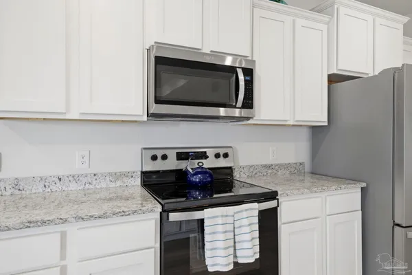 a kitchen with stainless steel appliances granite countertop white cabinets and a stove a microwave oven with white cabinets