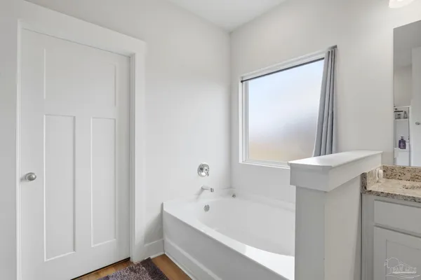 a bathroom with a tub a sink and a mirror