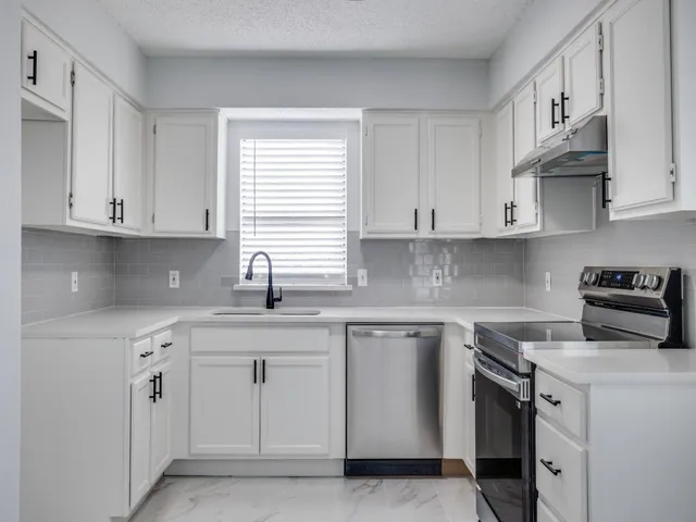 a kitchen with cabinets appliances a sink and a window