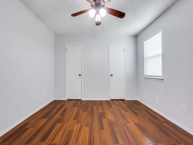 a view of a room with wooden floor and a ceiling fan