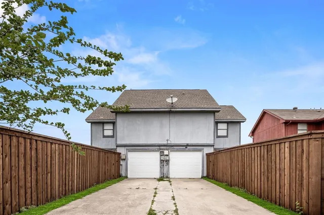 a view of a white house with a small yard and a wooden fence