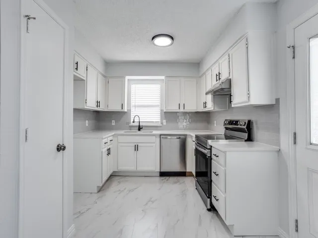 a kitchen with cabinets appliances a sink and a window
