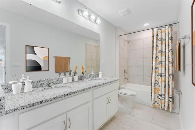 a bathroom with a granite countertop sink a toilet a mirror and shower