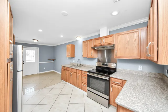 a kitchen with stainless steel appliances granite countertop a stove a sink and a refrigerator