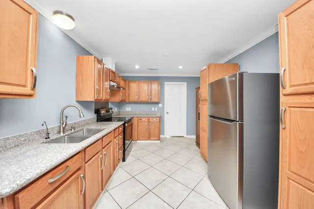 a kitchen with stainless steel appliances granite countertop a refrigerator sink and white cabinets