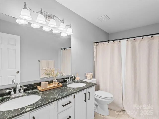 a bathroom with a granite countertop sink a toilet and a mirror