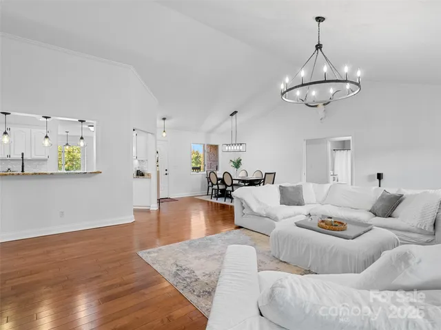 a living room with furniture kitchen view and a chandelier