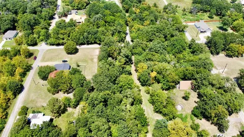 an aerial view of residential house with outdoor space and trees all around