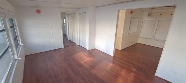 an empty room with wooden floor and entrance