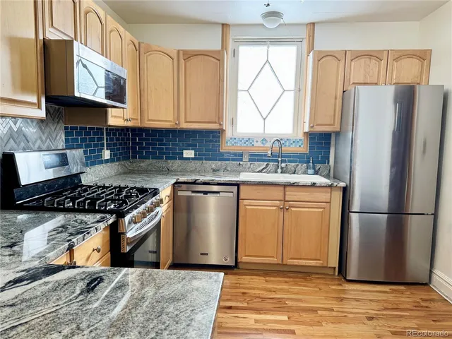 a kitchen with stainless steel appliances granite countertop a refrigerator stove and sink