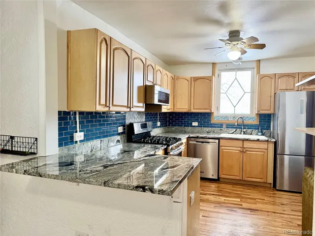 a kitchen with stainless steel appliances granite countertop a stove a sink a refrigerator and a microwave