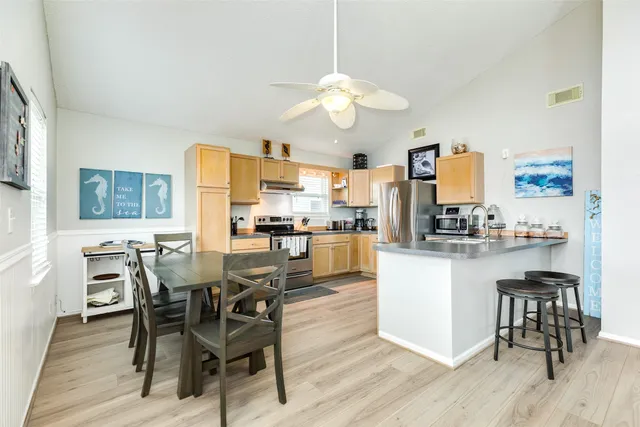 a kitchen with stainless steel appliances a dining table chairs stove and white cabinets