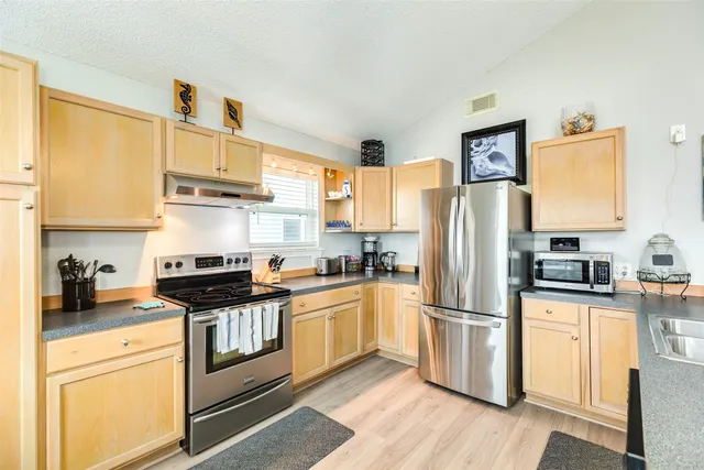 a kitchen with granite countertop a refrigerator stove top oven and sink