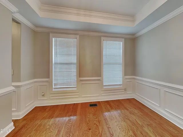 a view of an empty room with wooden floor and window